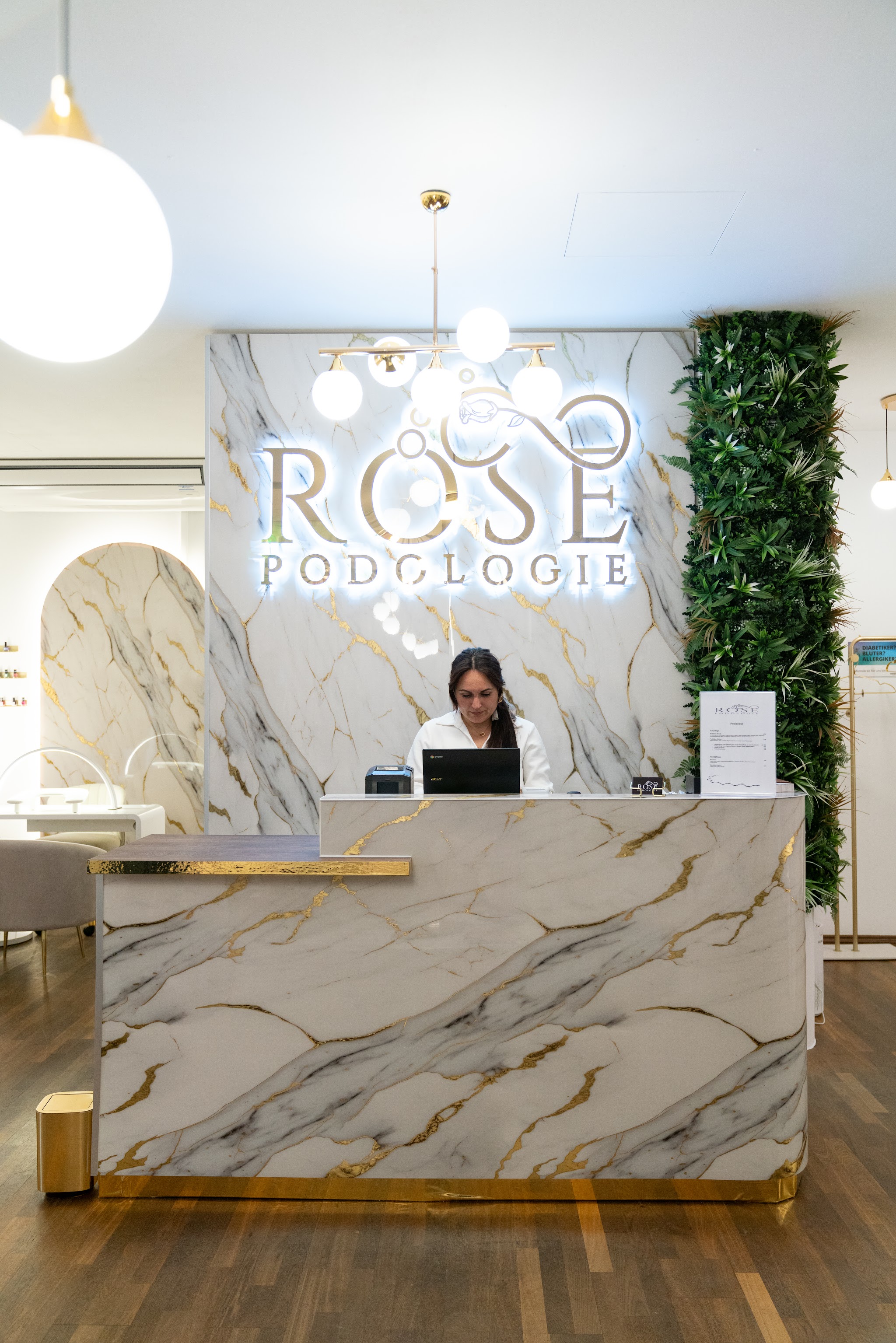 Empfangsbereich von Rose Podologie in Wels mit beleuchtetem Logo