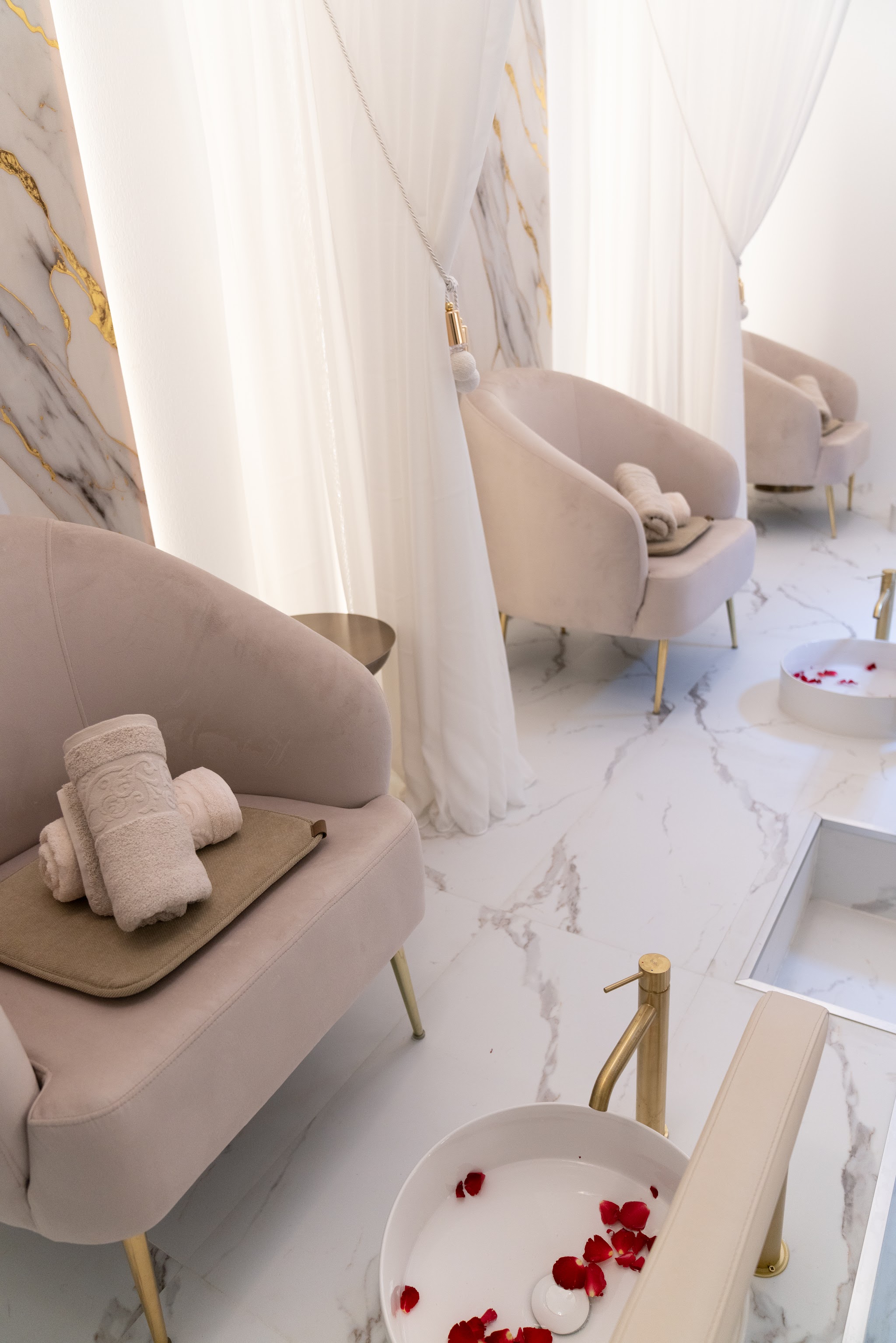 Reihe Pediküre-Sessel mit Rosenblättern im Fußbad