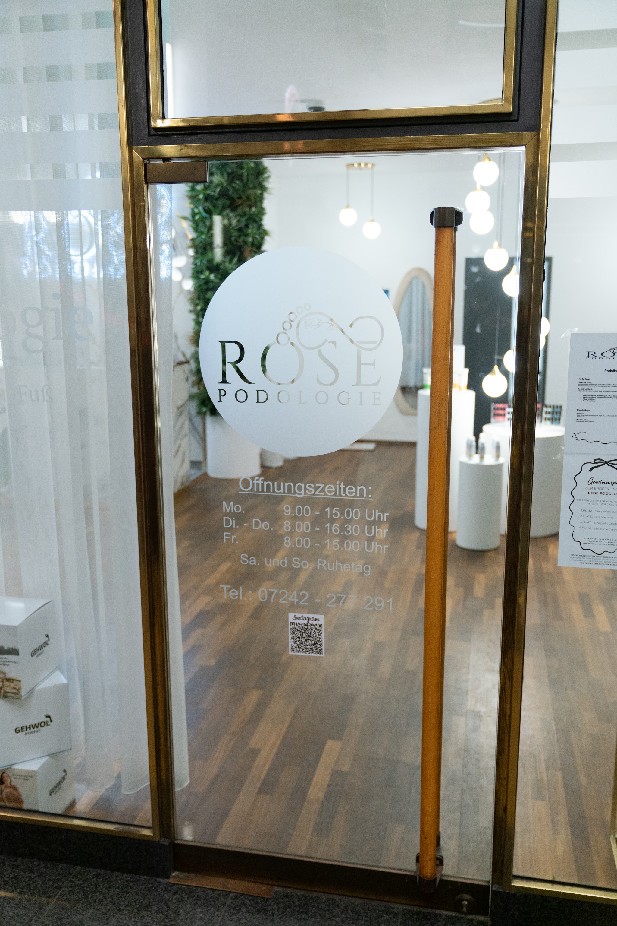 Eingang von Rose Podologie mit Logo und Öffnungszeiten an der Tür